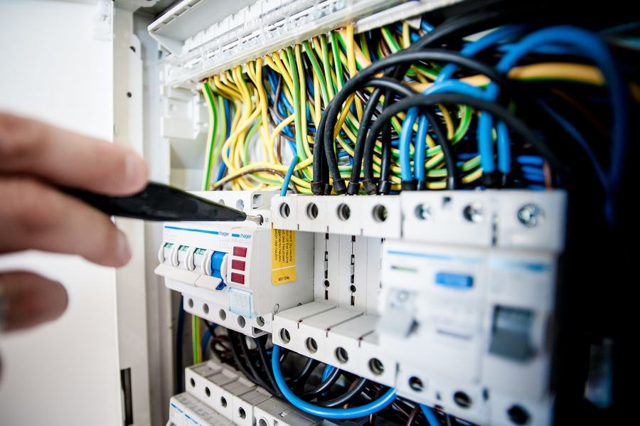 Main d'électricien désignant avec un tournevis les disjoncteurs d'un tableau électrique ouvert